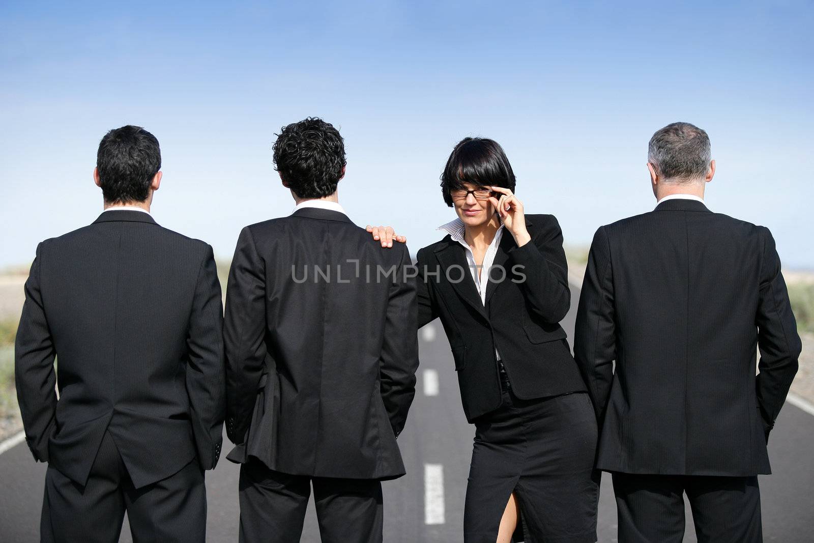 Woman in suit standing near men in suit by phovoir