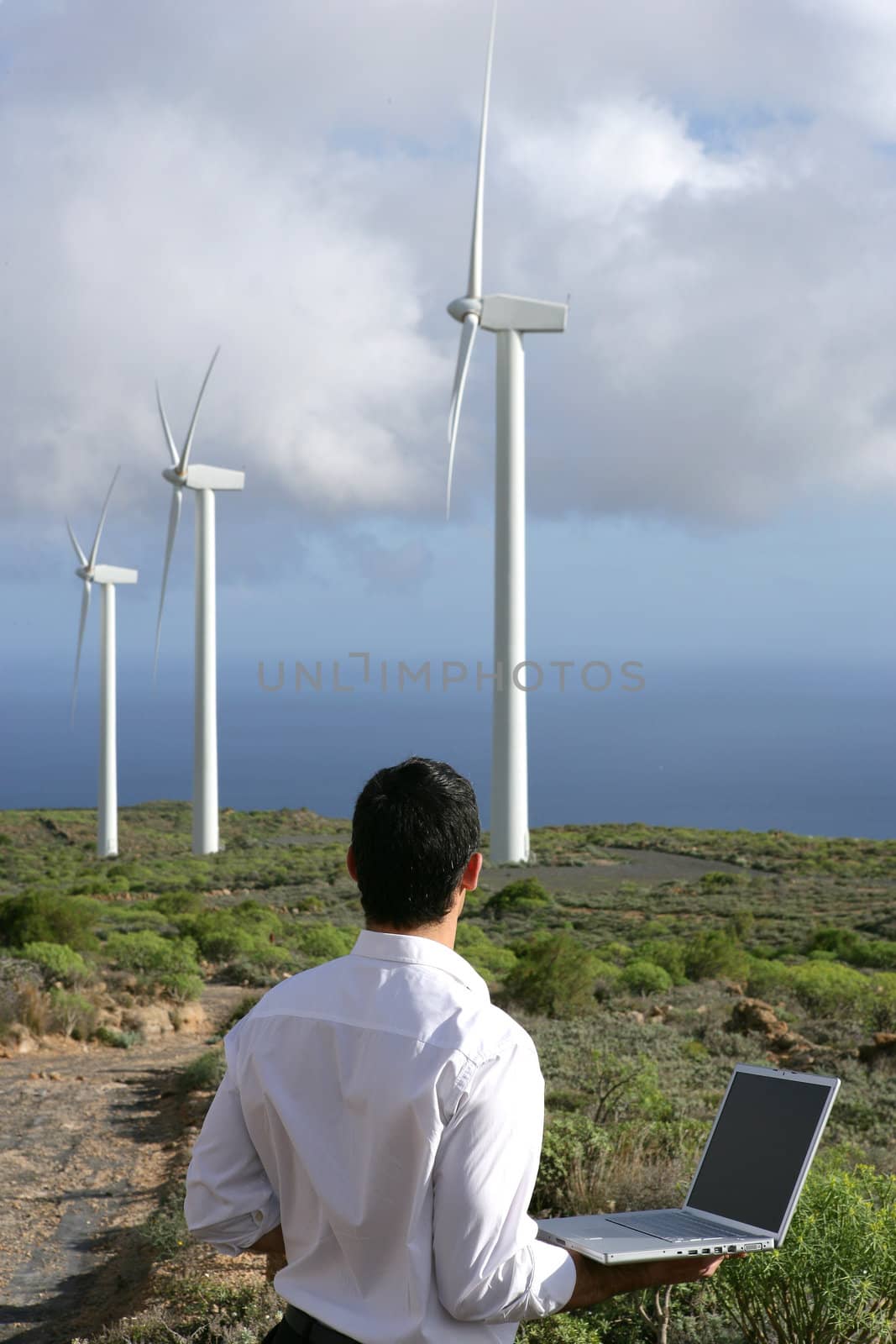 Man with computer watching wind turbines