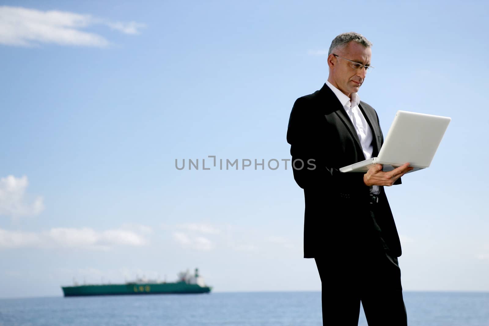 Businessman using his laptop at the coast