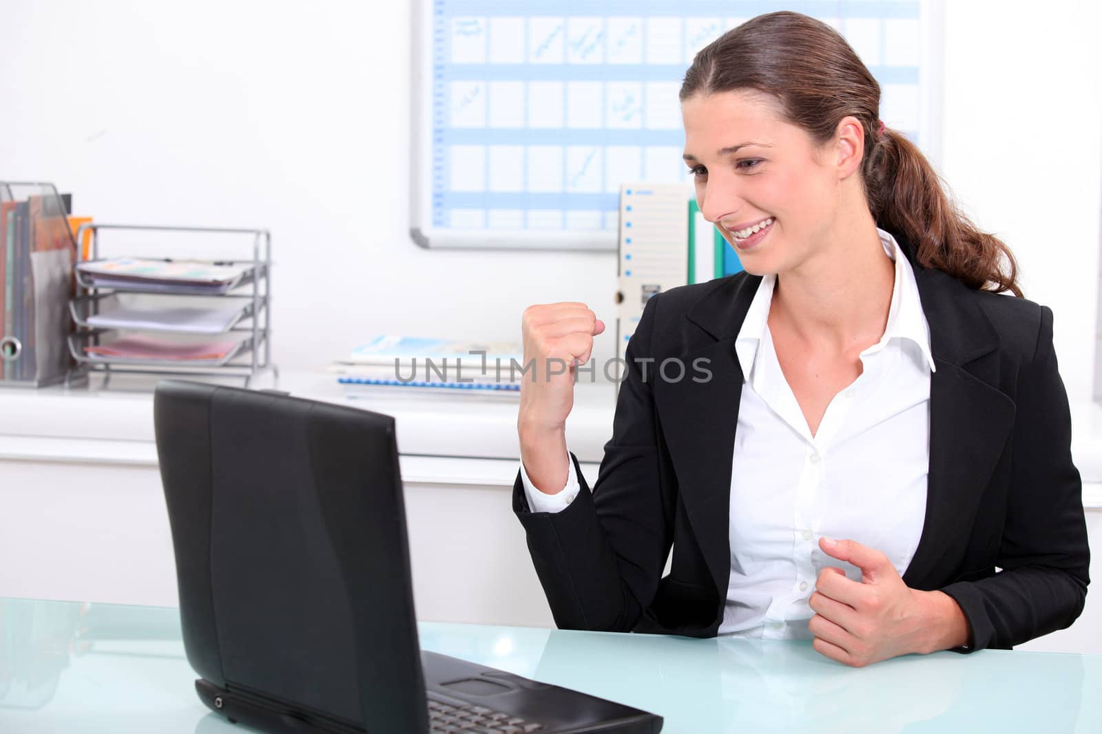 Smart woman punching the air in delight after looking at her laptop