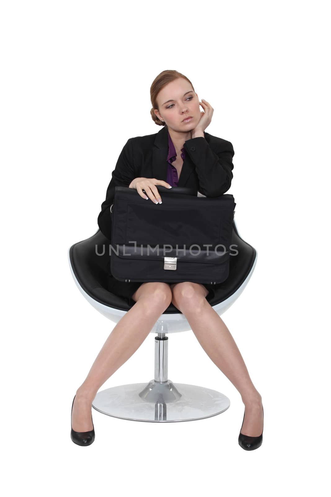 Austere businesswoman sitting in a chair with a briefcase on her lap