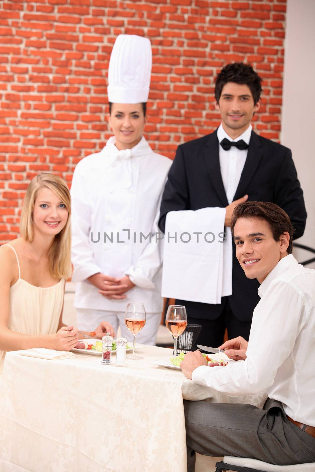 A couple being served by a waiter and a chef in a restaurant by phovoir