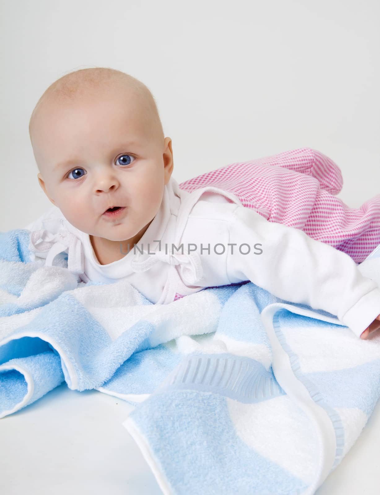 surprised beautiful baby lying on a blue towel