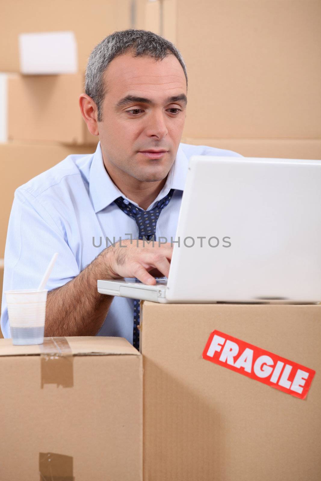entrepreneur with laptop amid removal boxes