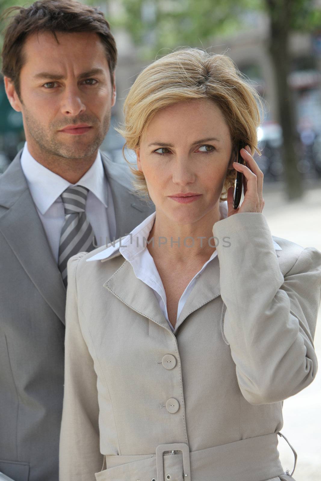 Businessman and woman using phone.