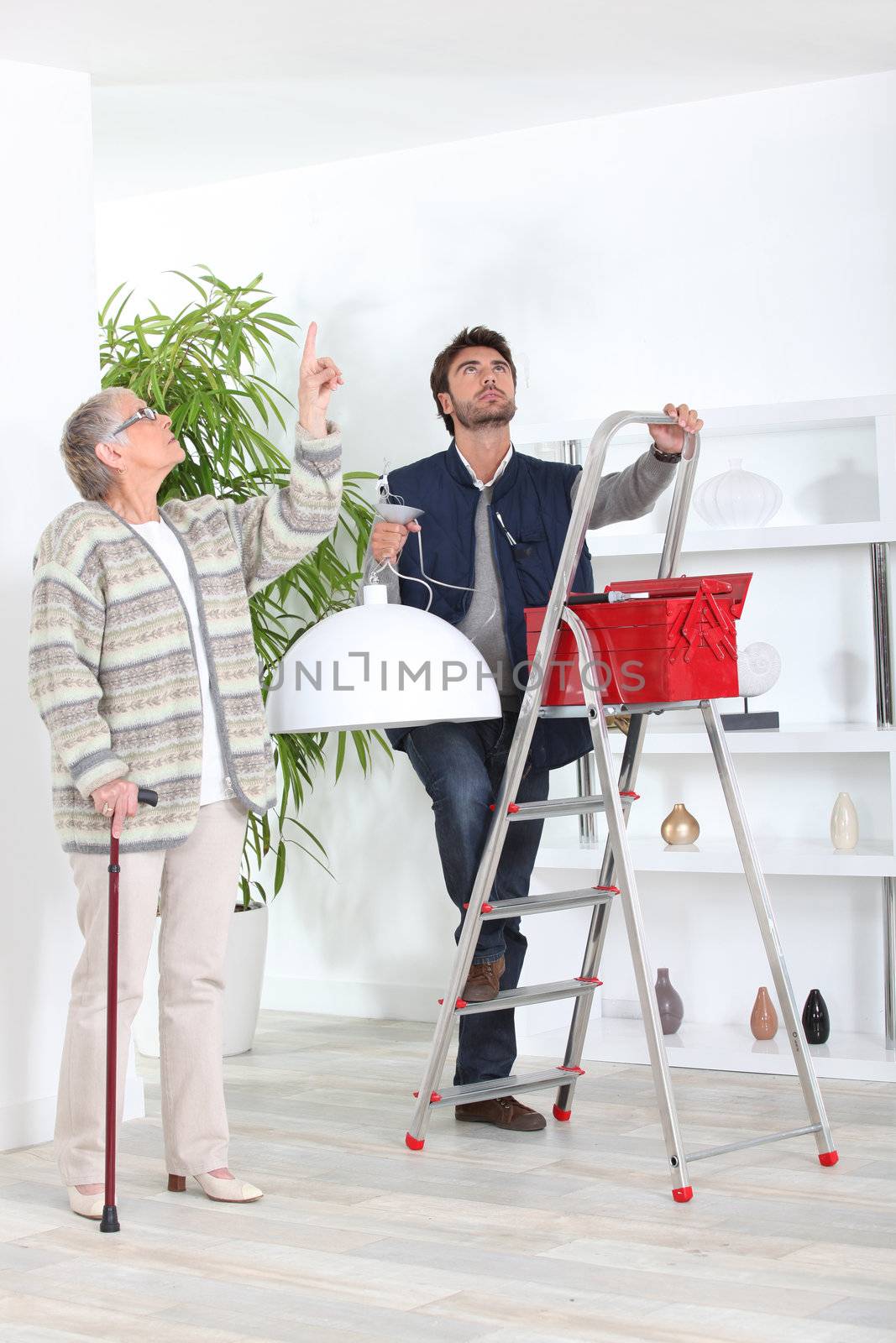 Man fitting ceiling light for old lady