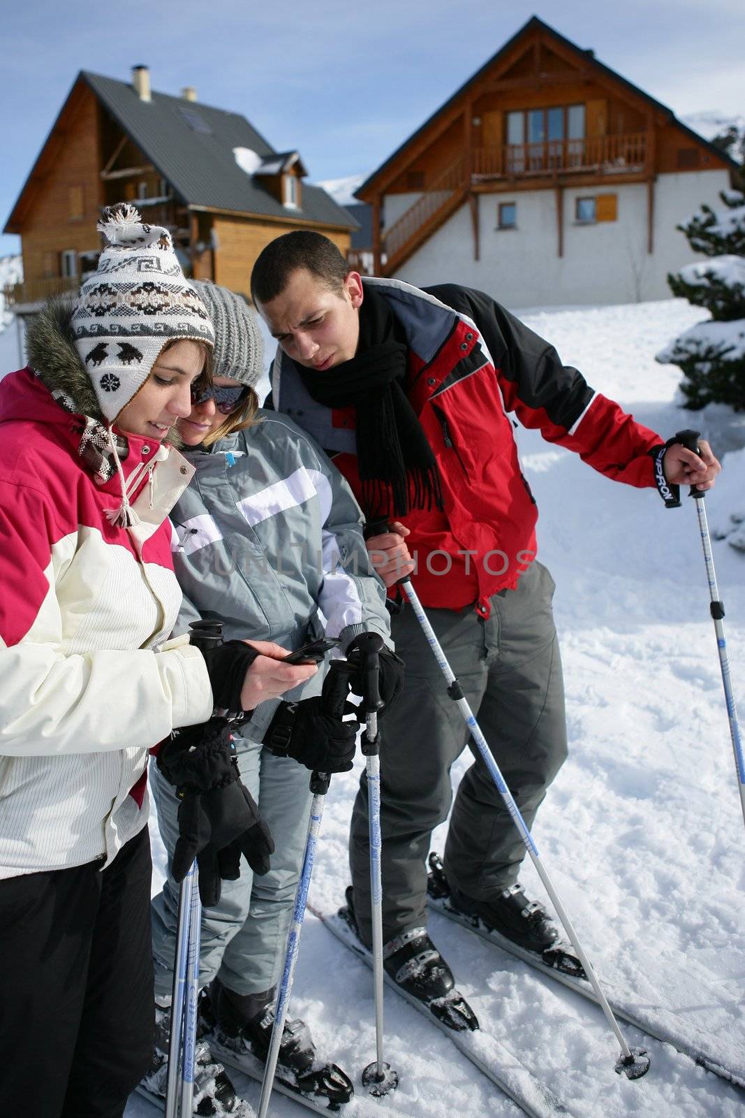 Ski teenagers looking at a phone by phovoir