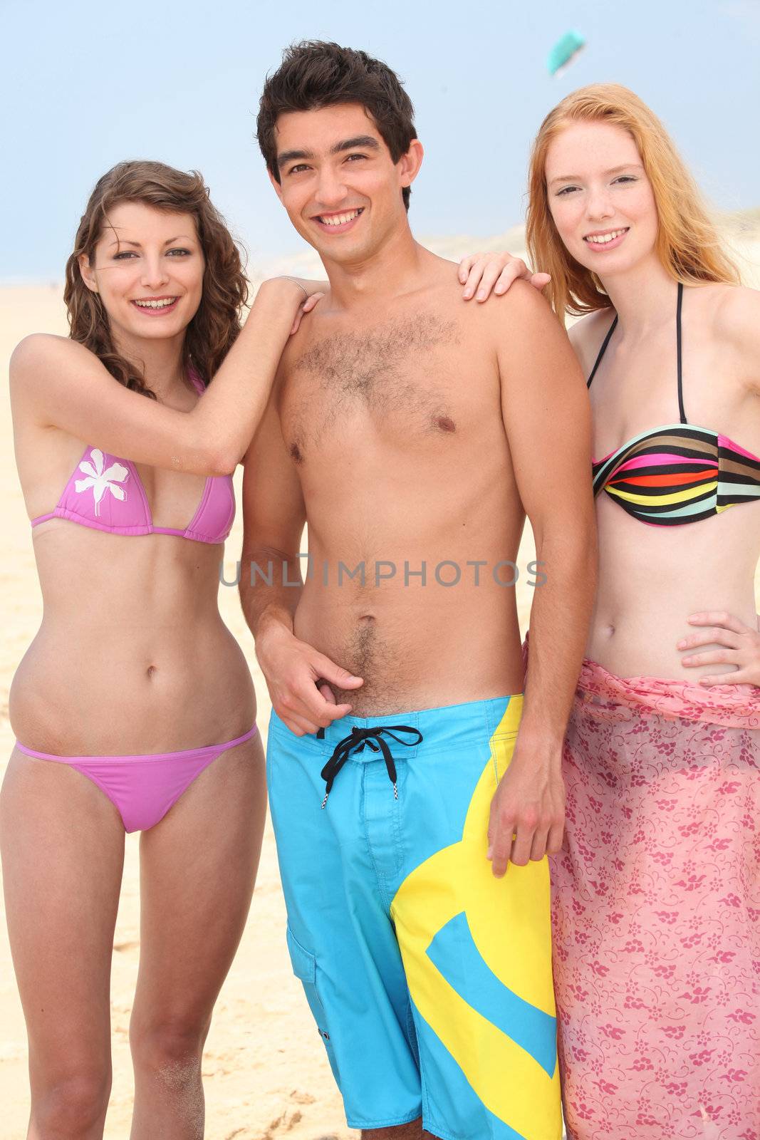 Three friends stood on a beach