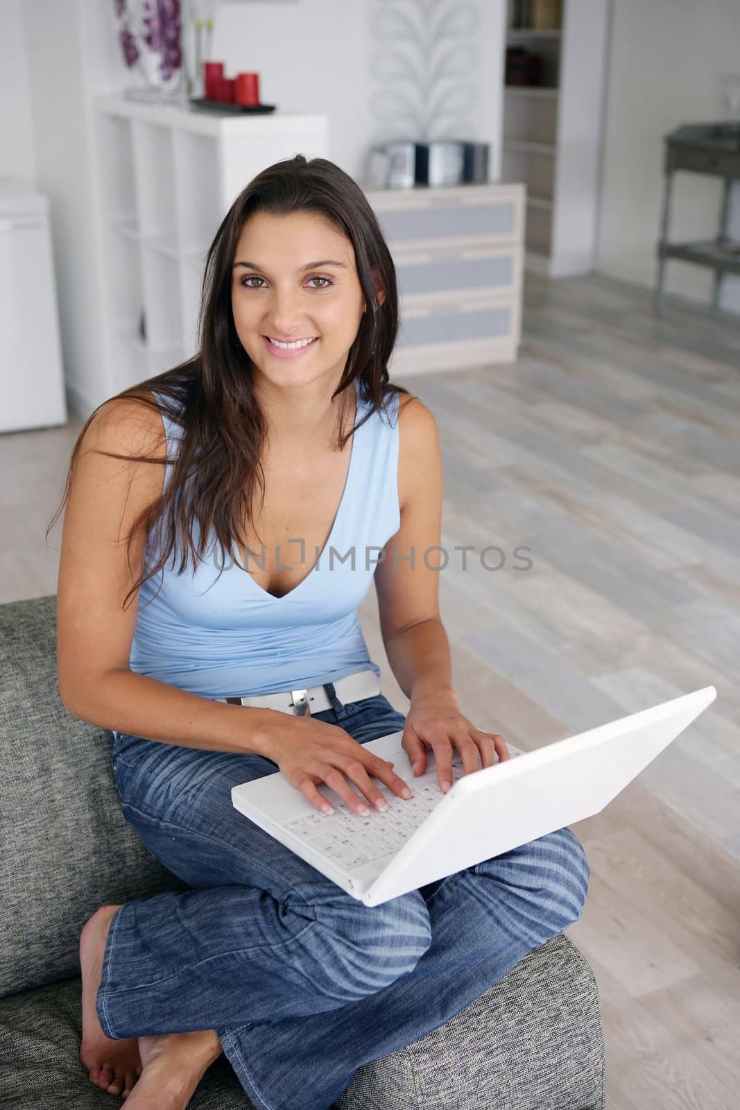 Smiling pretty woman with laptop on a sofa