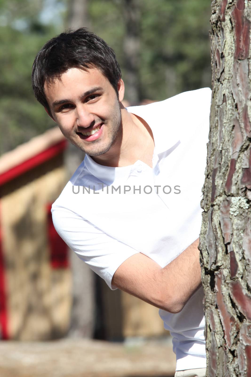 Man playing peekaboo around a tree