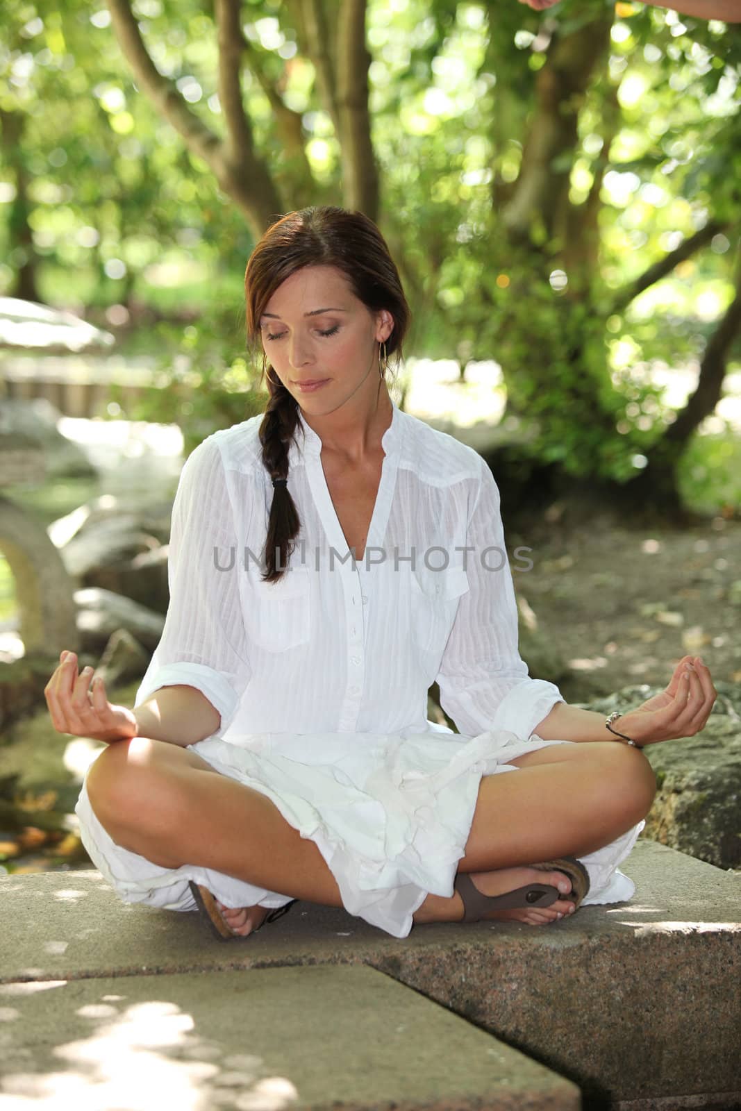 Woman in white sitting cross legged in the park