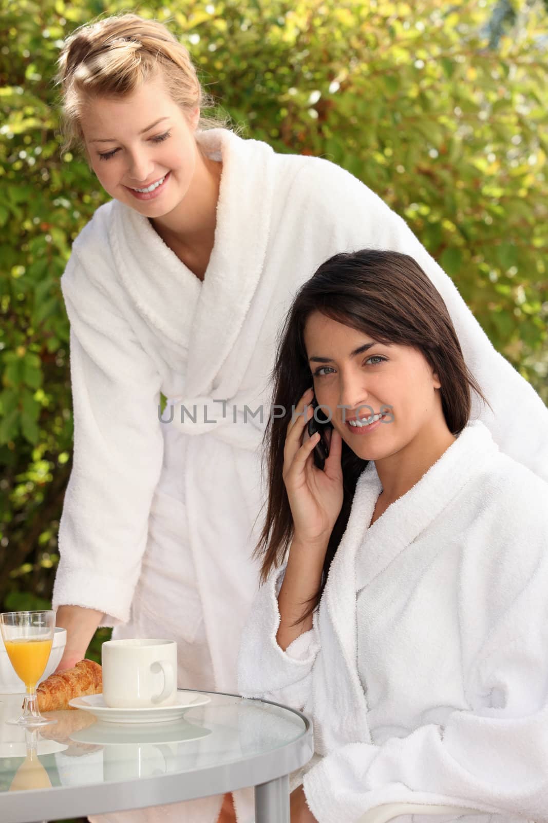 Young women breakfasting outside and taking a call