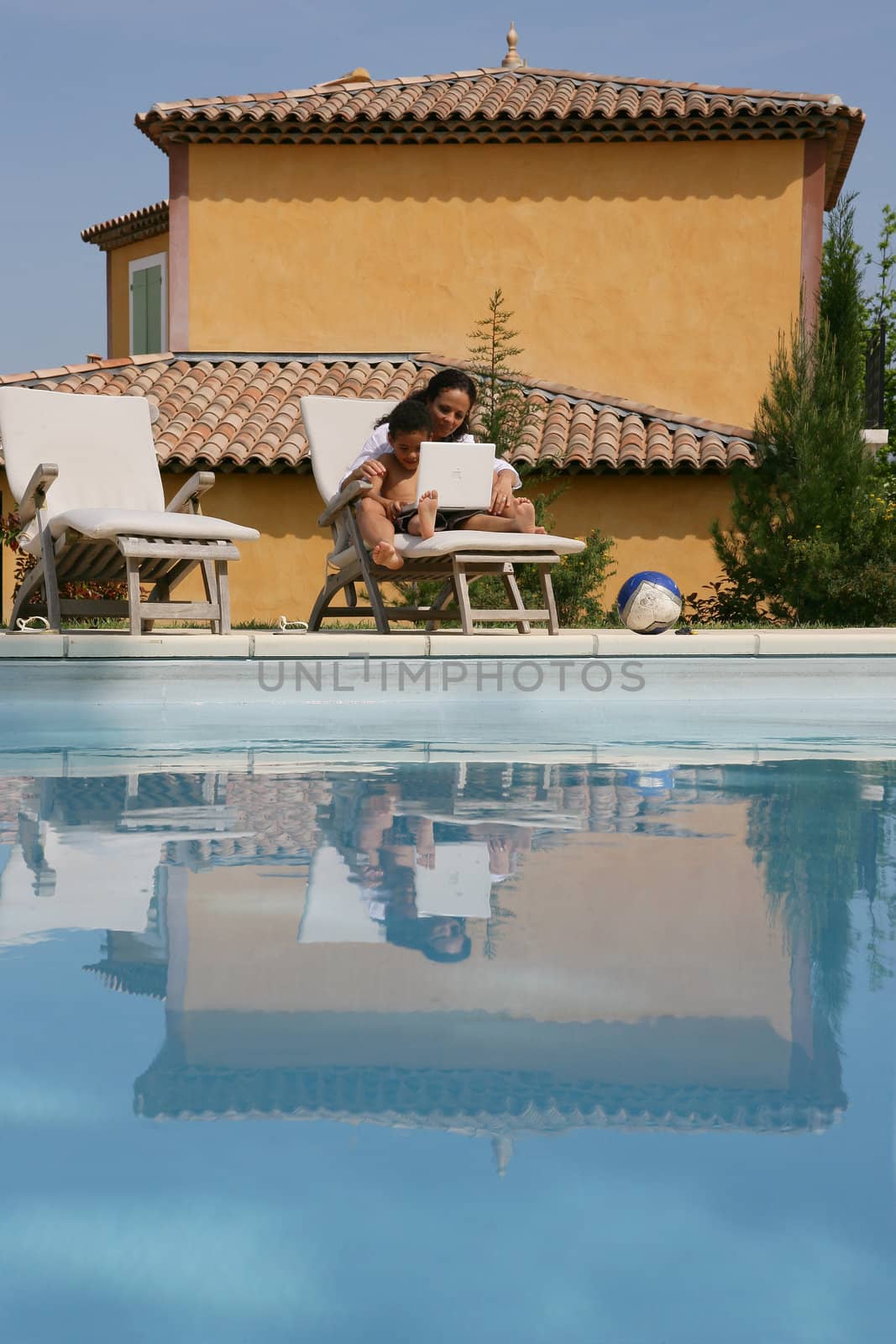 Mother and son poolside with laptop