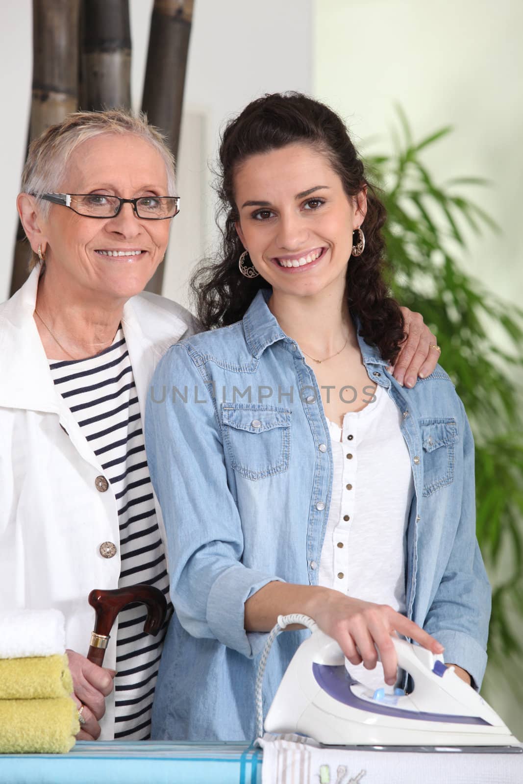 Young woman ironing for an elderly lady