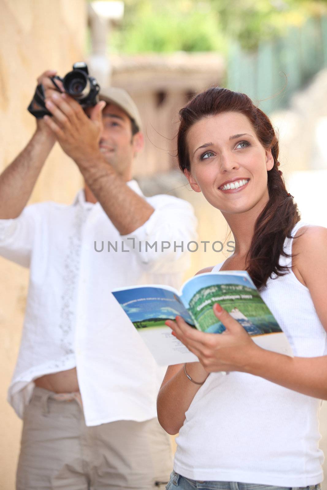 Tourists with camera and travel guide by phovoir