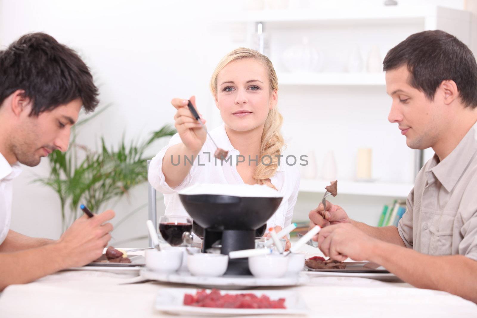 Three friends enjoying chocolate fondue