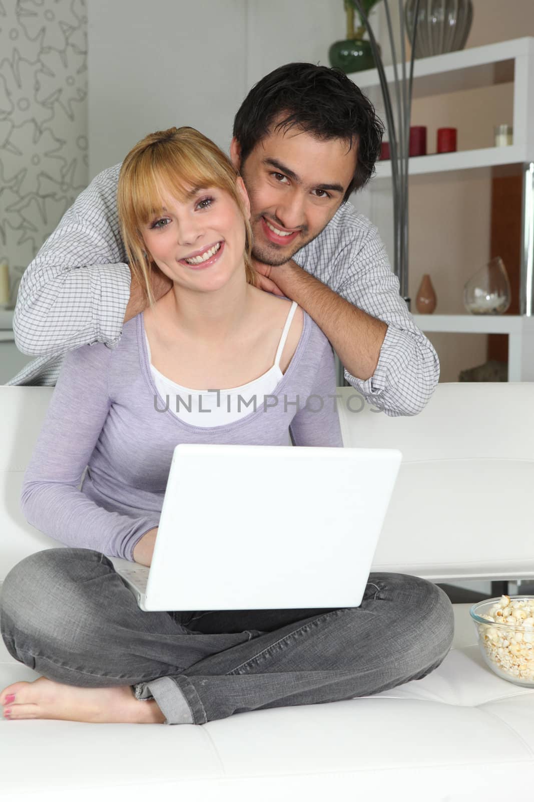 Young woman and young man smiling with laptop at home by phovoir