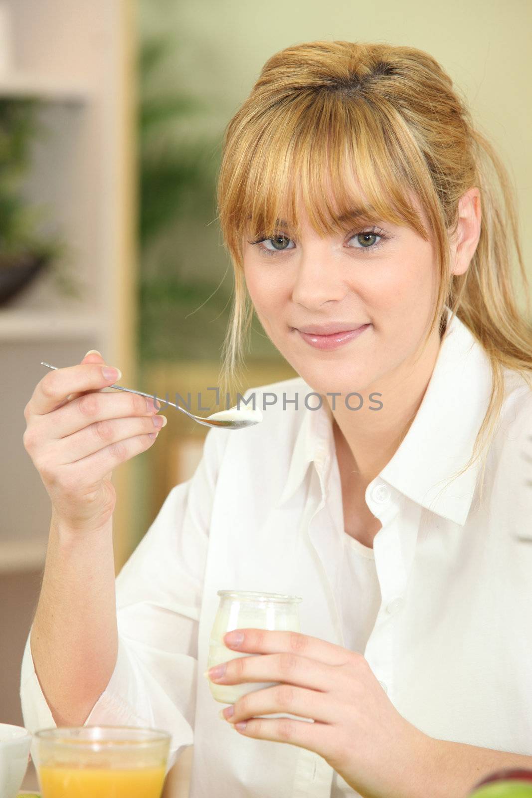 Young woman eating yoghurt at breakfast