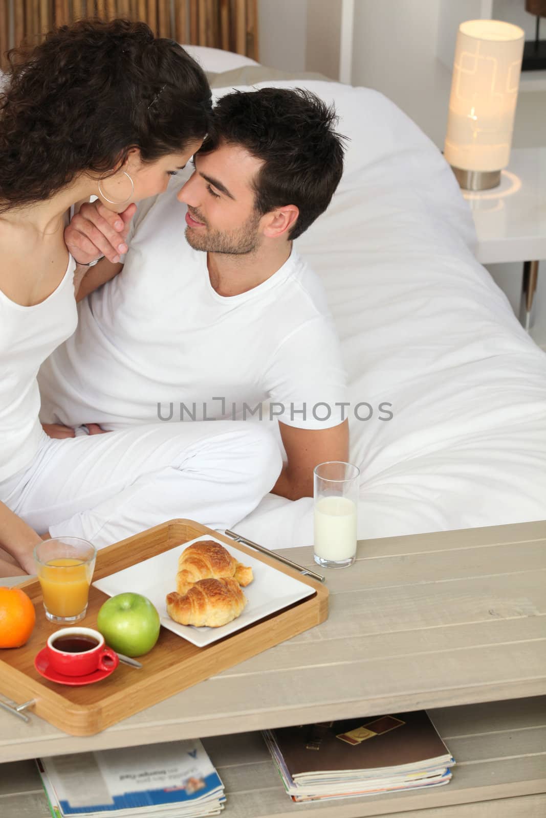 Clothed couple kissing in bed