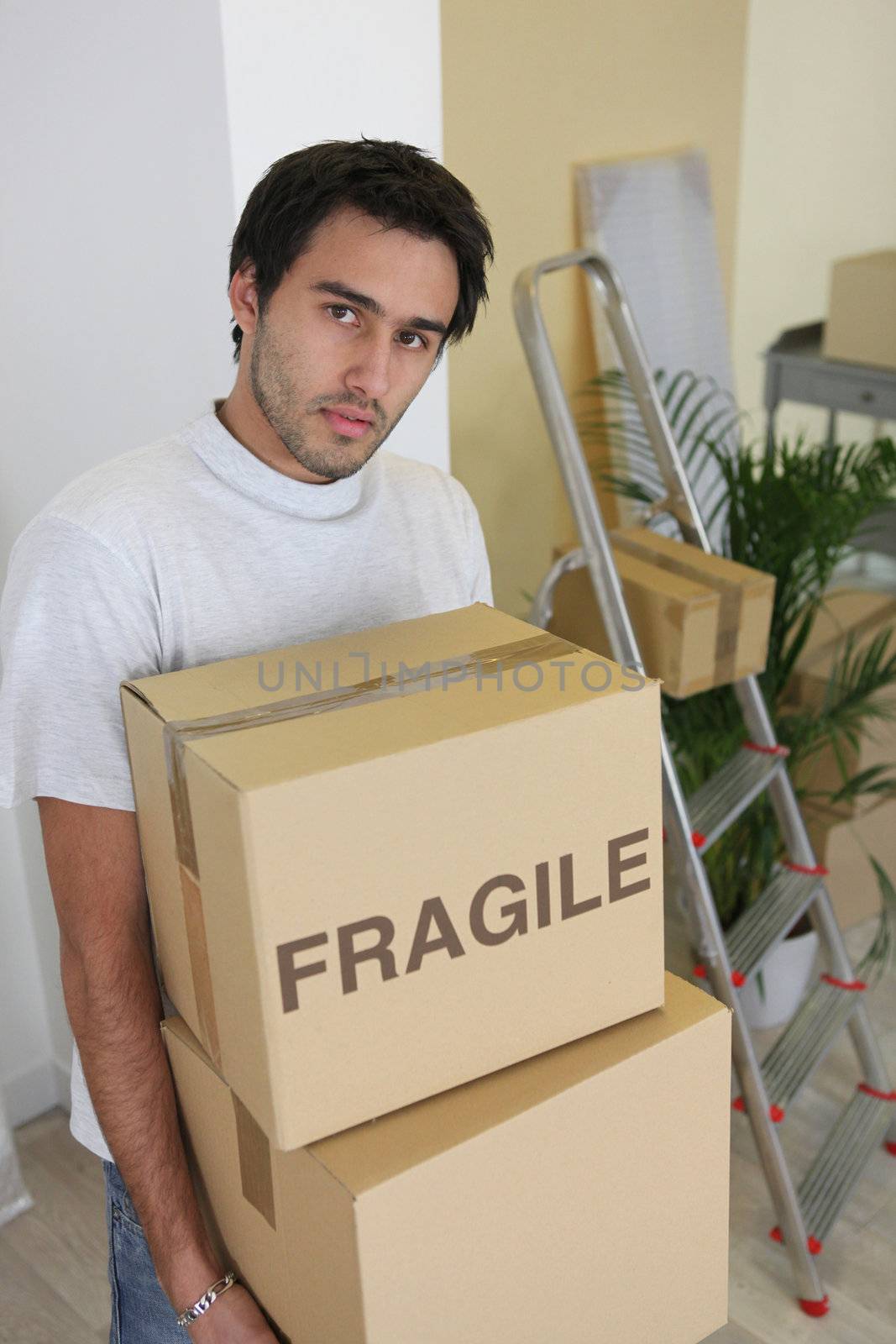 Young man carrying cardboard boxes on moving day