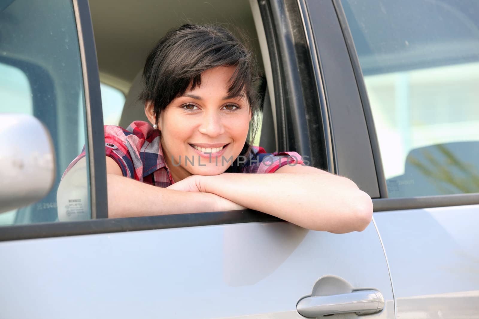Young woman leaning out of the window of a car by phovoir
