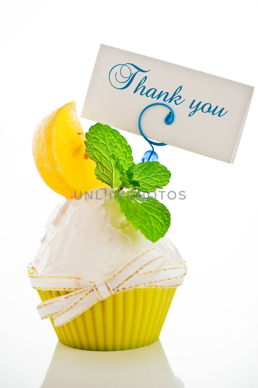 A refreshing lemon cupcake with a leaf of mint and a label for your text on white background as a studio shot