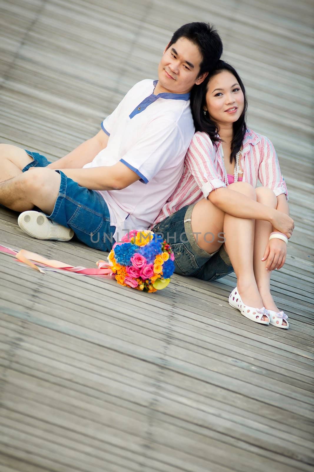portrait of romantic couples sitting over wooden pier