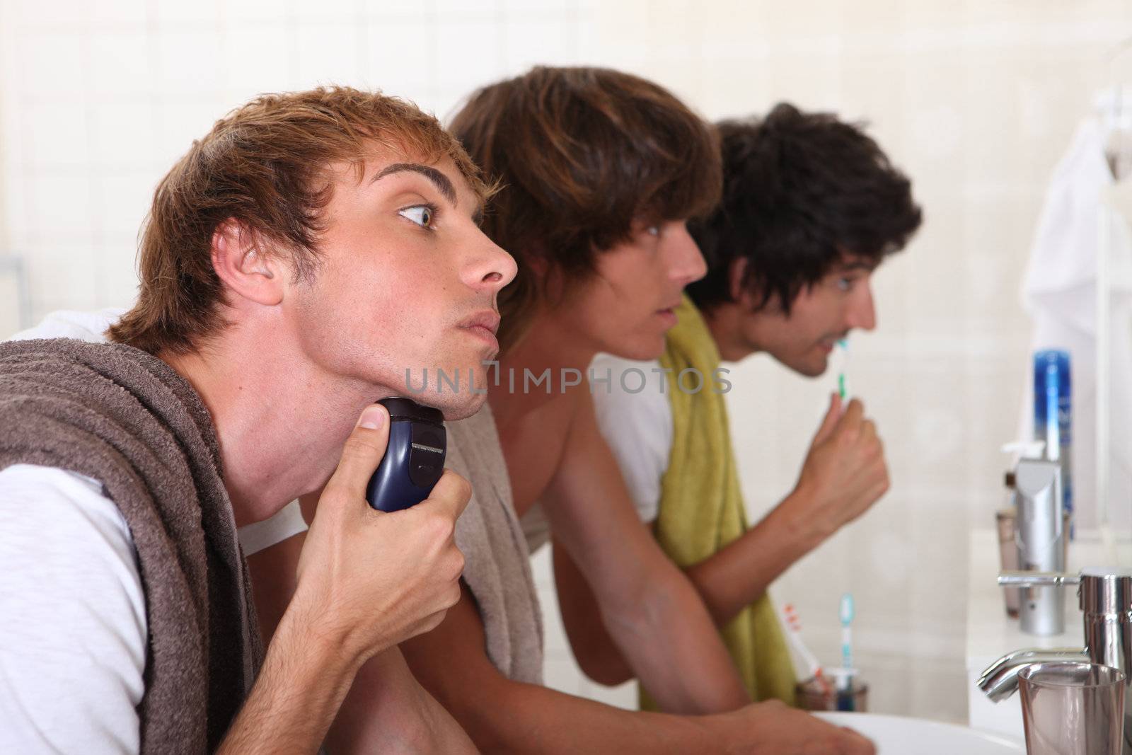 Three young men in the bathroom getting ready to go out by phovoir