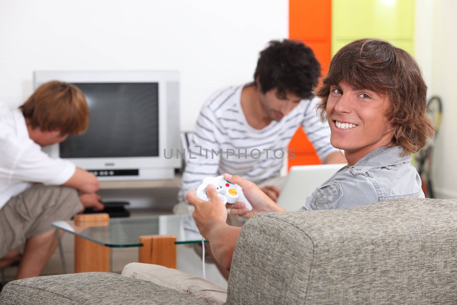 Three male teenagers relaxing at home by phovoir