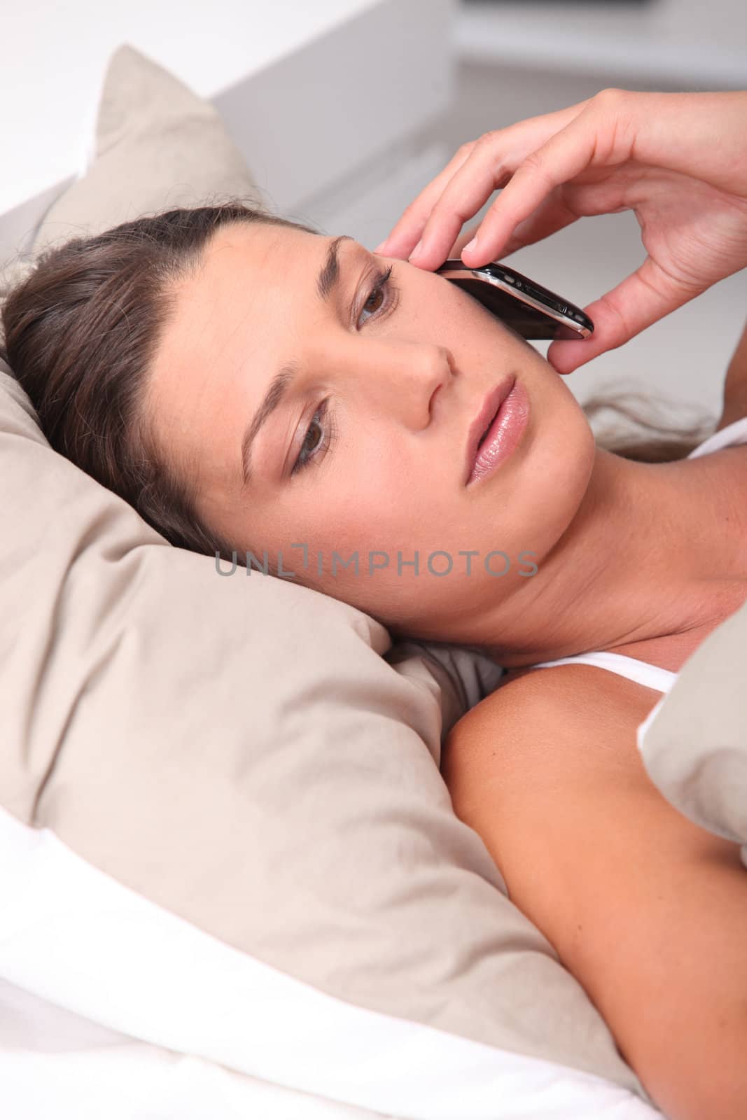Woman laid in bed speaking on telephone