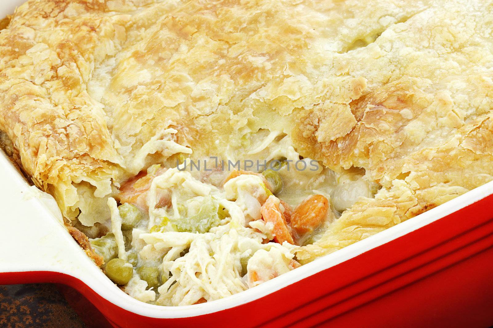 Above view of fresh Chicken Pot Pie with wooden spoon. Section of pot pie removed to reveal chicken, carrots and peas.                    

