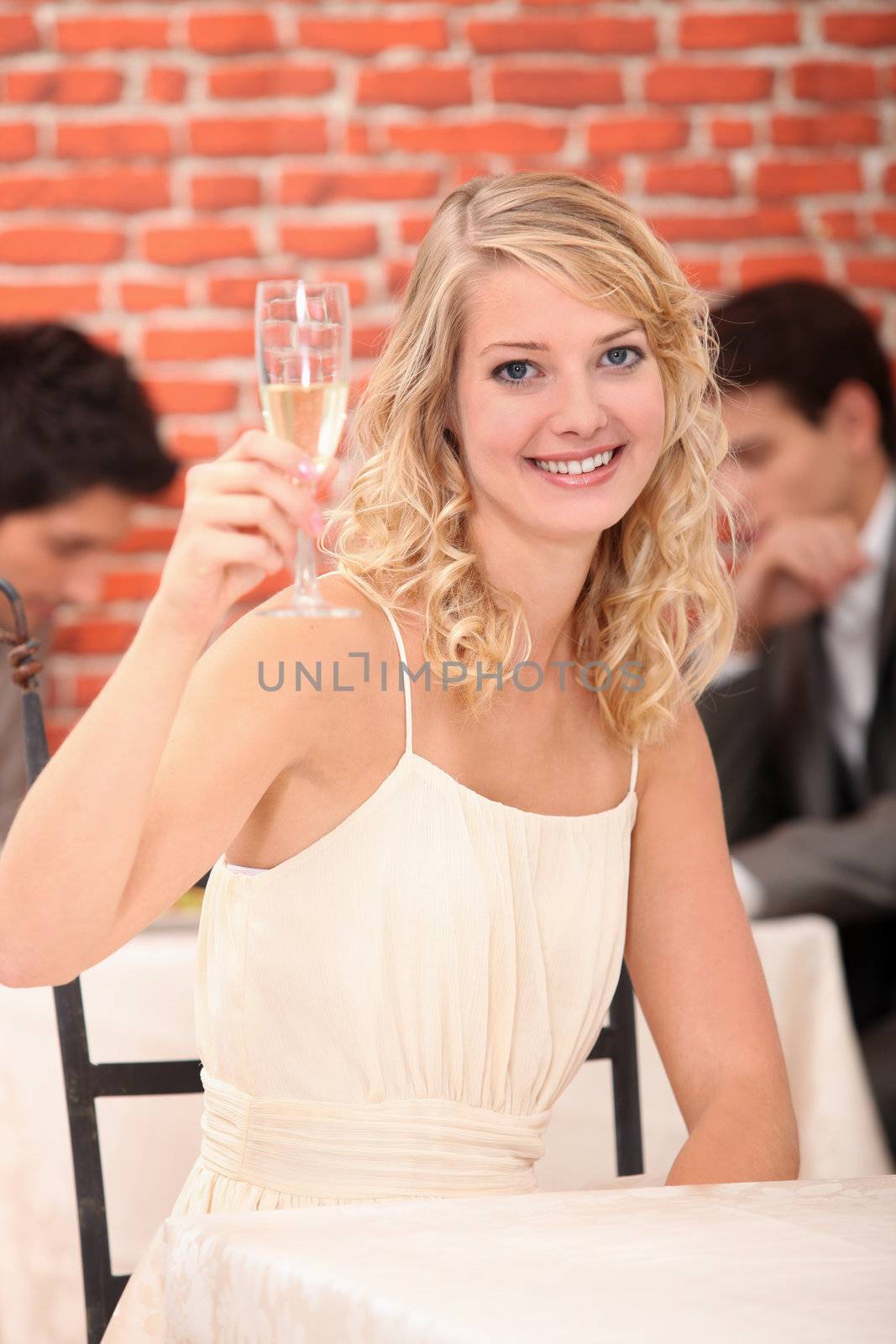 Blonde woman with a glass of white wine by phovoir