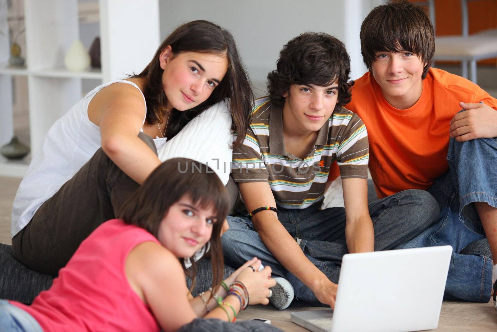 teenagers having fun with a laptop at home by phovoir