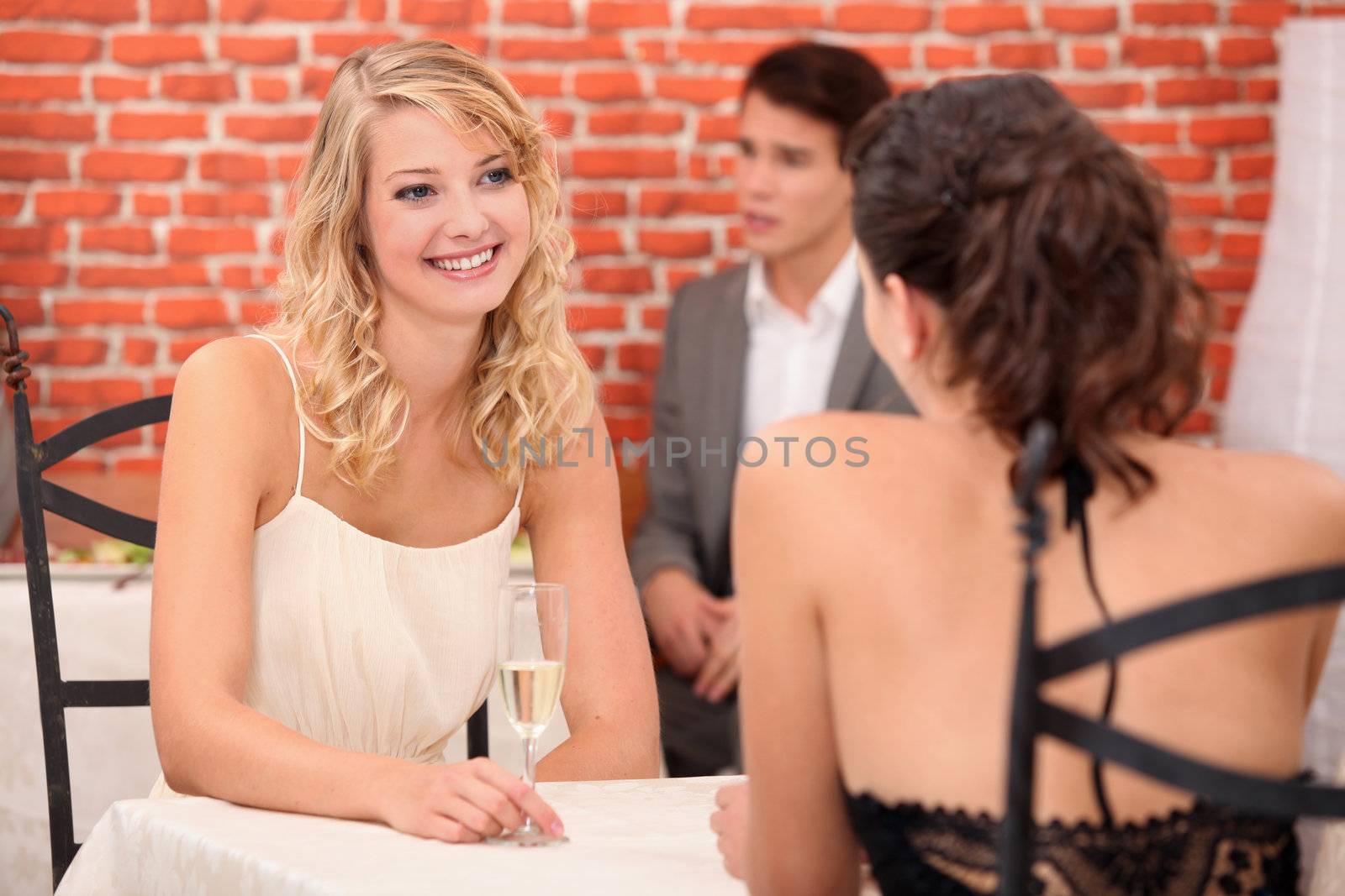 A couple of women drinking champagne in a restaurant.