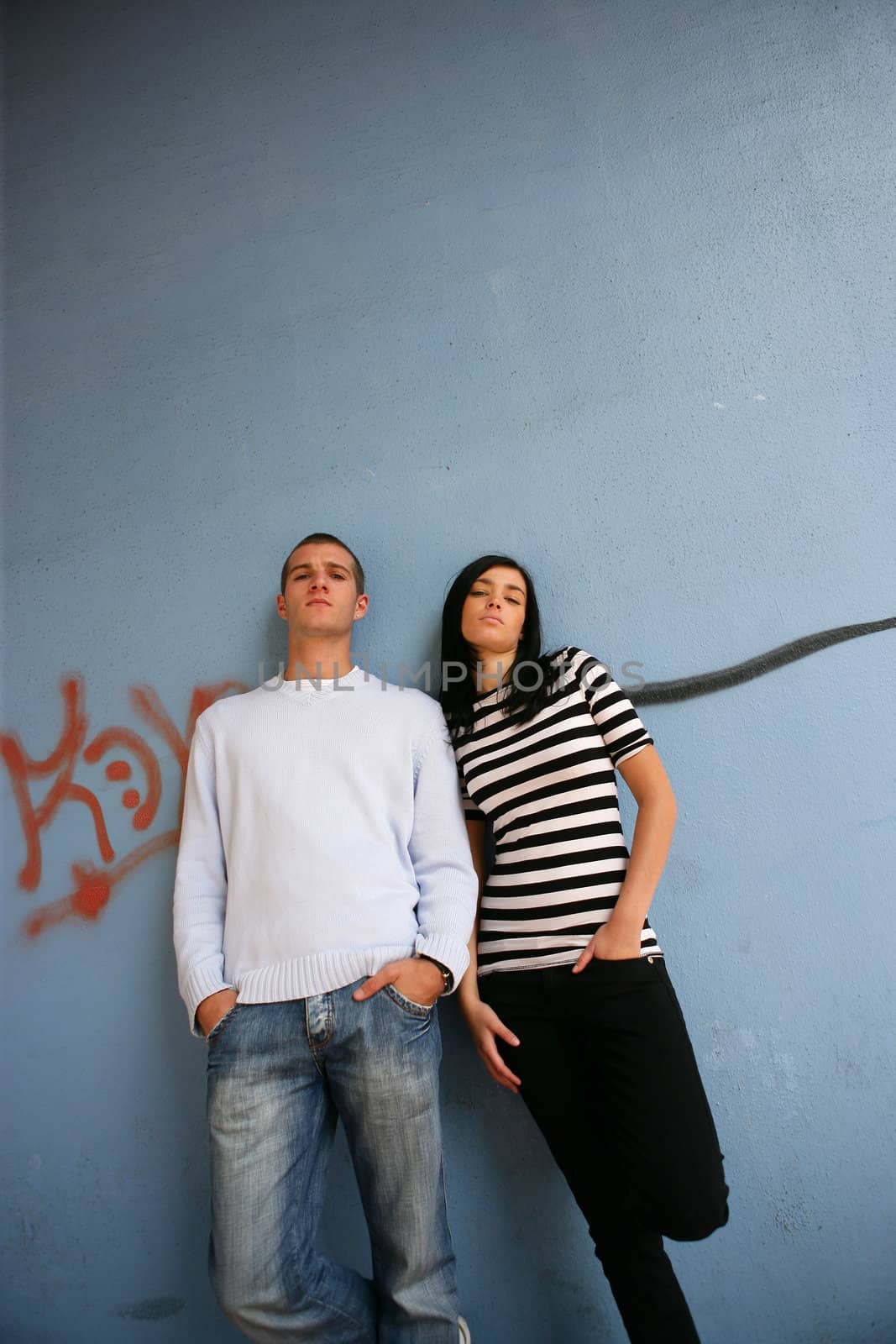 Young man and young woman leaning on a wall