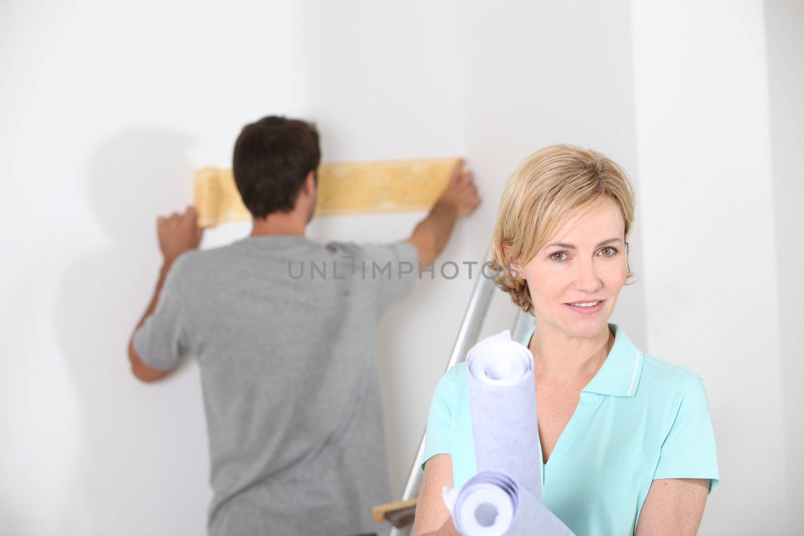 Couple preparing to wallpaper a white room