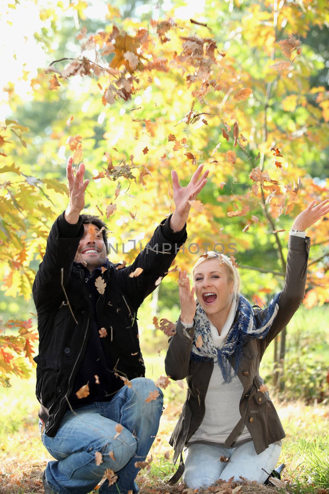 Couple playing with autumn leaves by phovoir