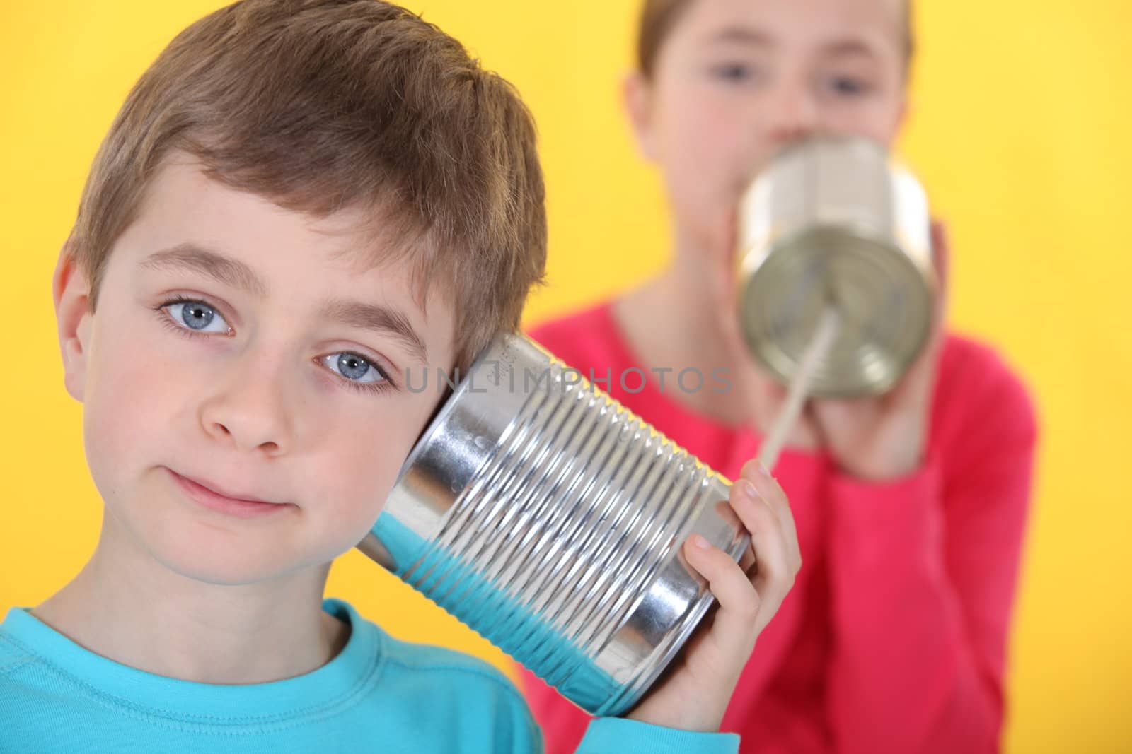 A brother and a sister talking through cans and a rope. by phovoir