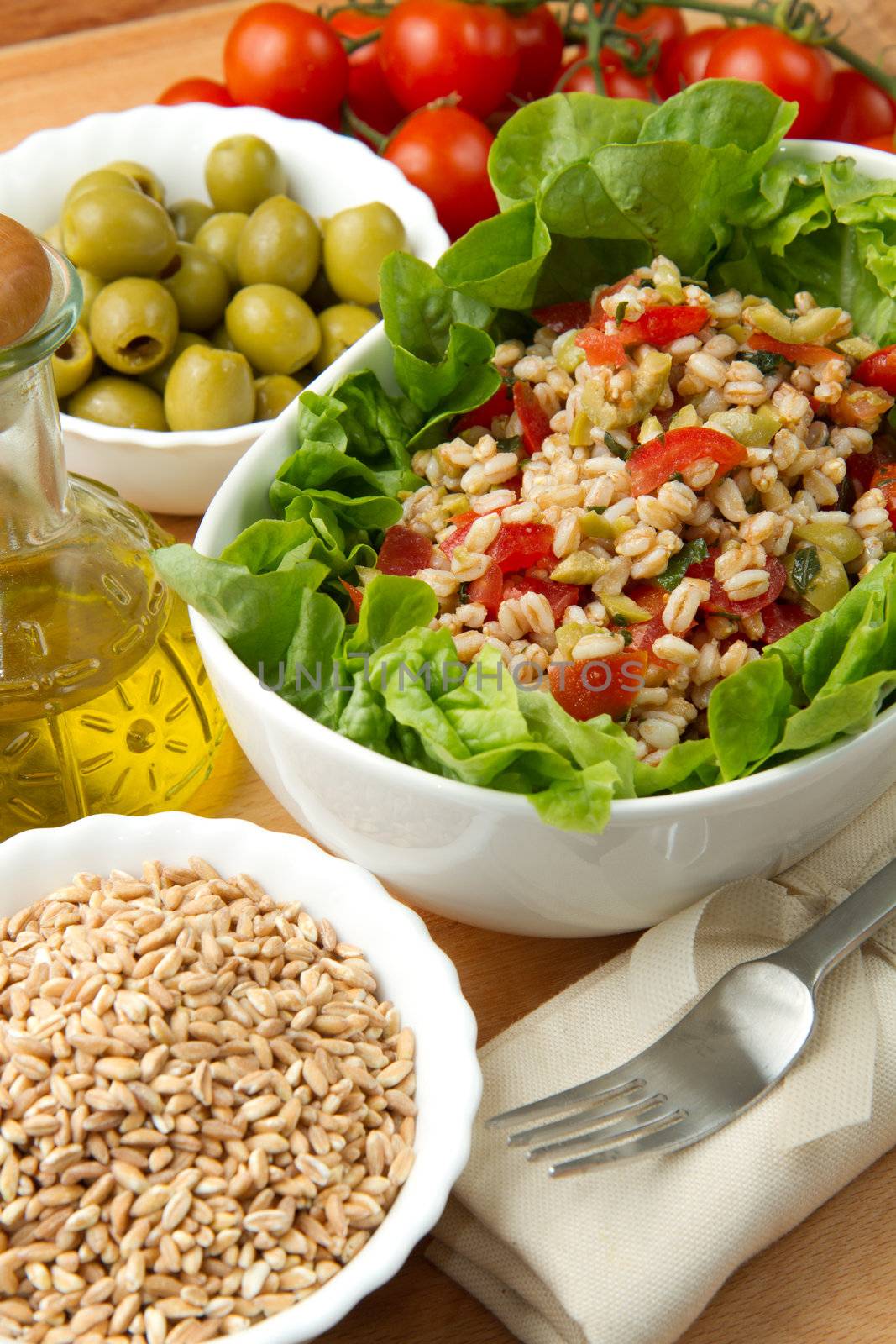 a dish with spelt salad with tomatoes,olive and salad