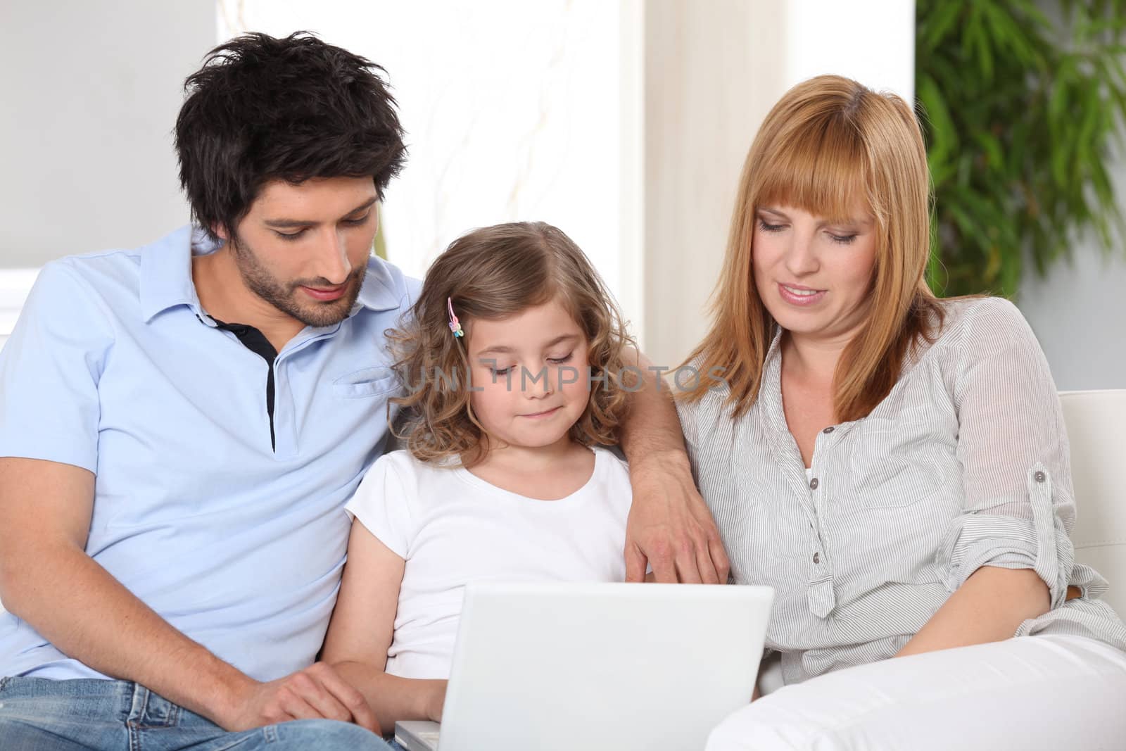 Parents helping their child with her homework by phovoir