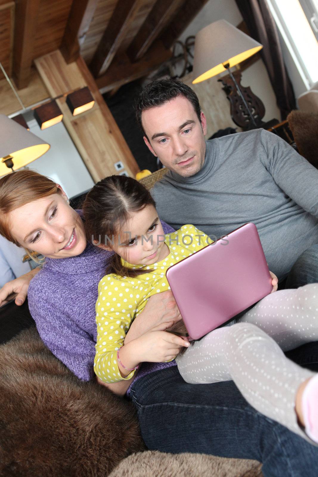 Parents using a pink laptop with their daughter