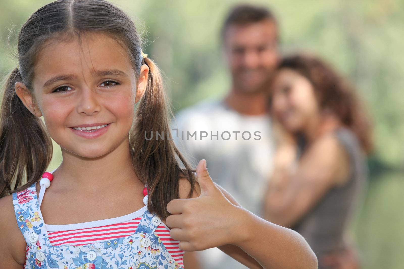Little girl giving thumbs-up gesture by phovoir