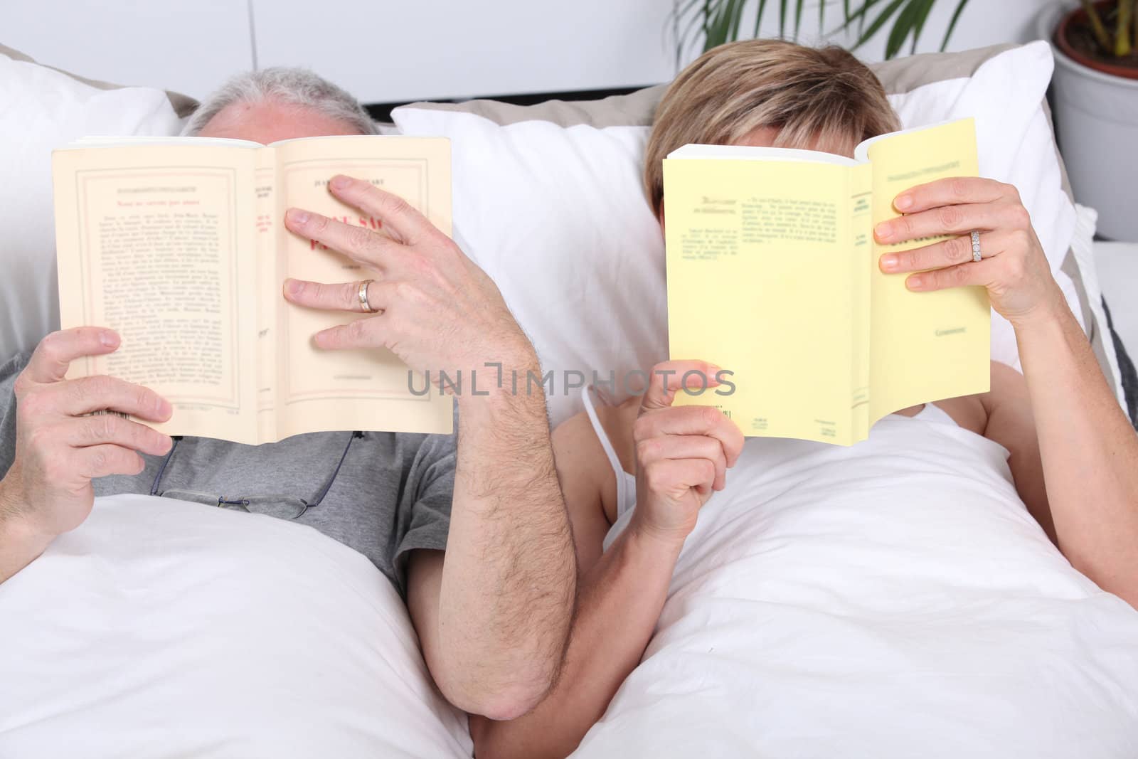 Couple reading together in bed by phovoir
