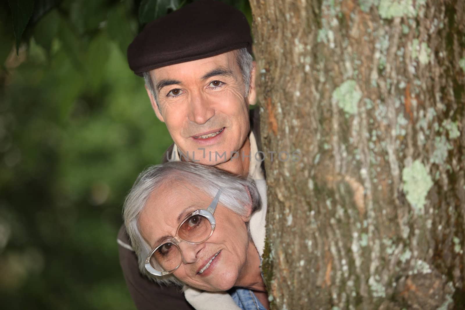 Elderly couple behind tree