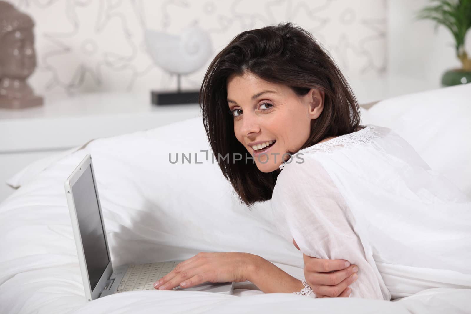 Woman using laptop lying on a bed