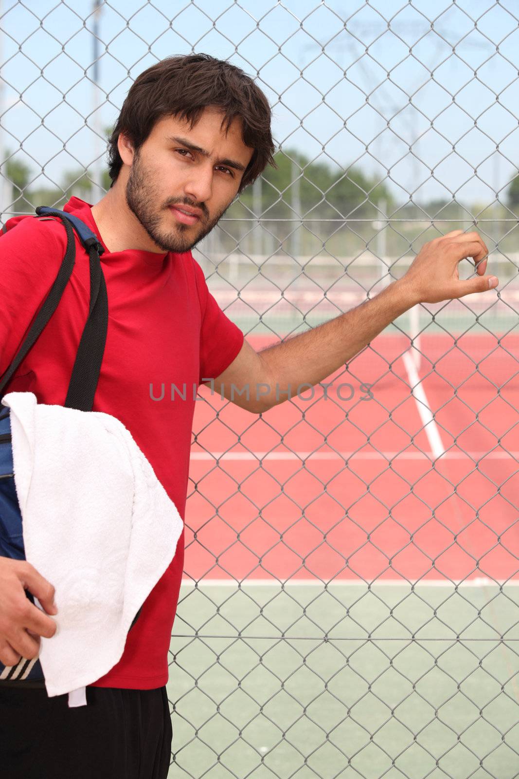 Young man outside a tennis court