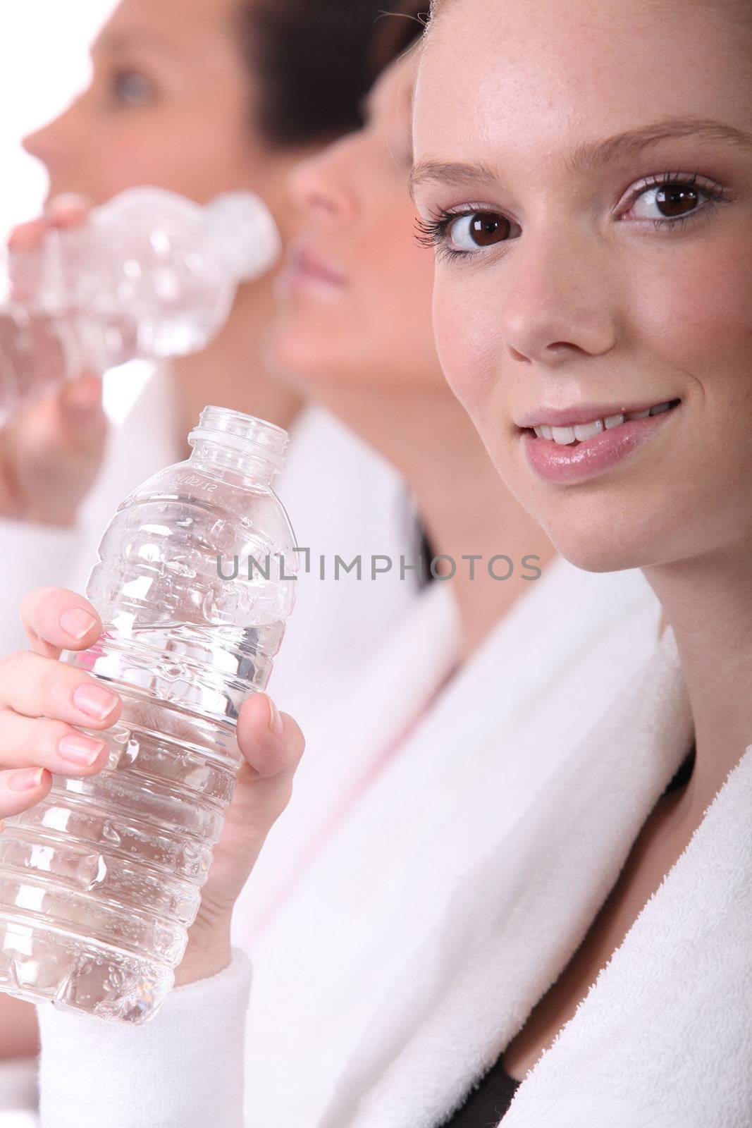 Women drinking water after a workout by phovoir