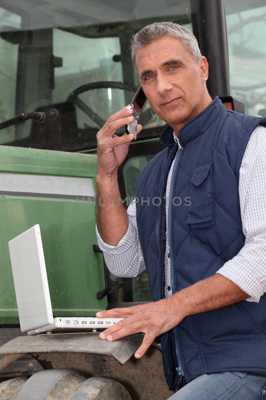 Farmer with a laptop and cellphone by phovoir