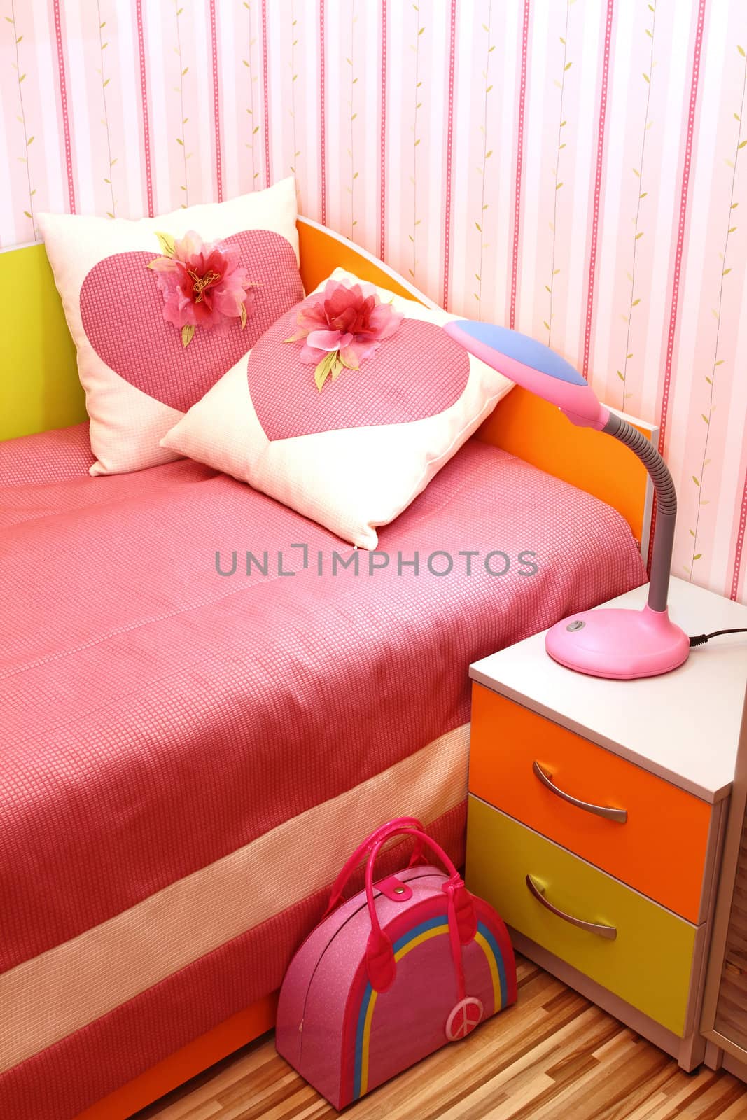 fragment of an interior of a bedroom. a bed with the small embroidered pillows, a row a bedside table and a lamp