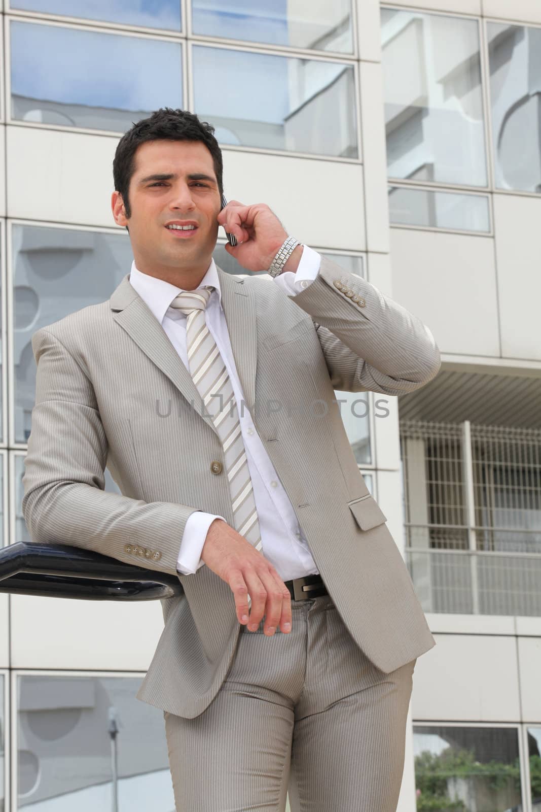Businessman stood outside office with mobile telephone